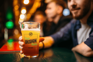 Man at bar of brewery holding custom YOUR LOGO HERE beer glass merch